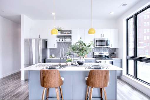 A modern kitchen with a large island and wooden chairs.
