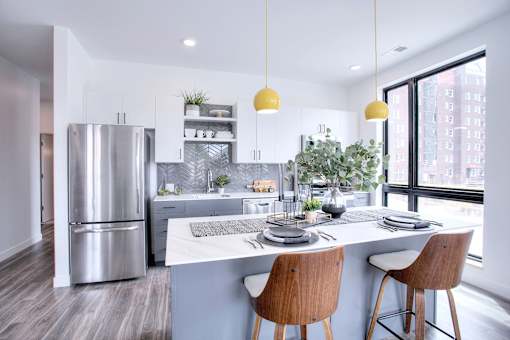 A modern kitchen with a stainless steel refrigerator and a breakfast bar.