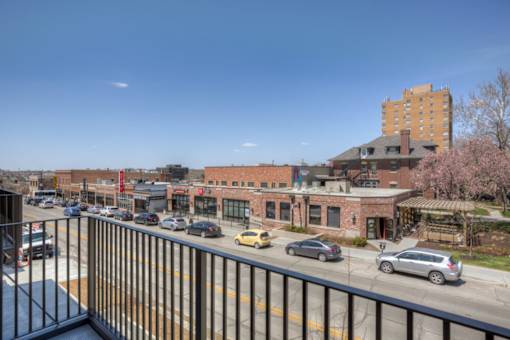 A view of a street from a balcony with cars and buildings.