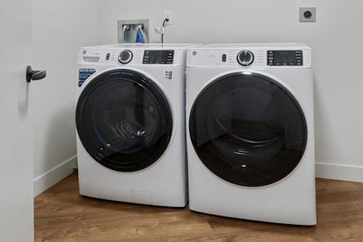 Two white front load washing machines in a laundry room.
