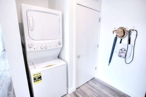A small white washing machine is in a laundry room.