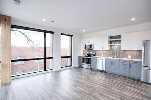 A modern kitchen with a view of apartment buildings outside the large windows.
