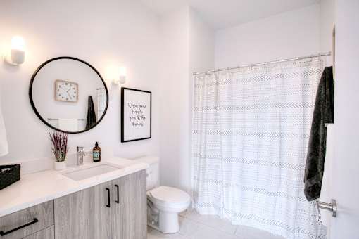 A bathroom with a white shower curtain and a towel hanging on the door.