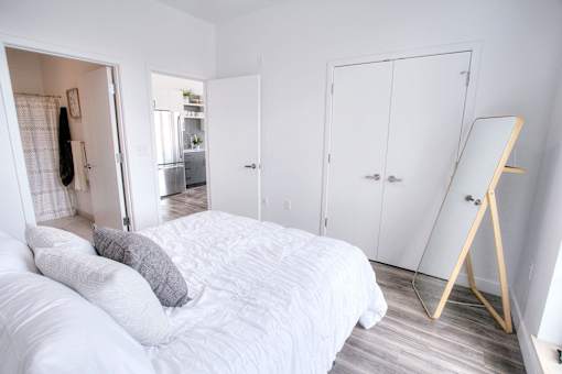 A white bedroom with a large bed and a mirror.
