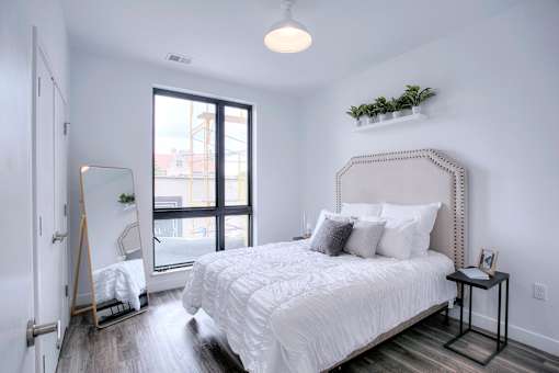 A bedroom with a large bed and a window overlooking a cityscape.