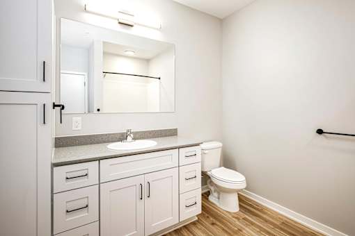 A white bathroom with a sink, toilet, and cabinets.