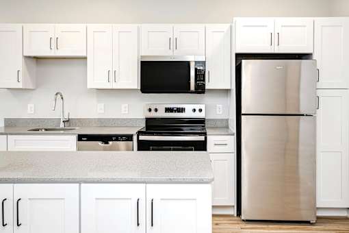 A kitchen with white cabinets and a stainless steel refrigerator.