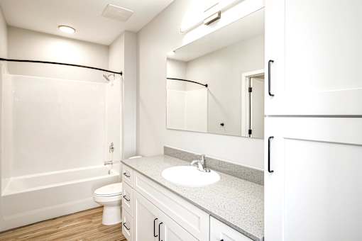 A white bathroom with a toilet, sink, and mirror.
