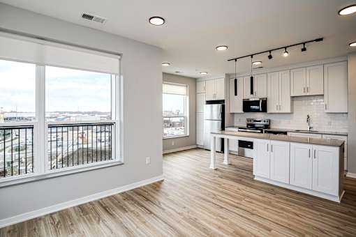 A kitchen with white cabinets and a large window overlooking a parking lot.