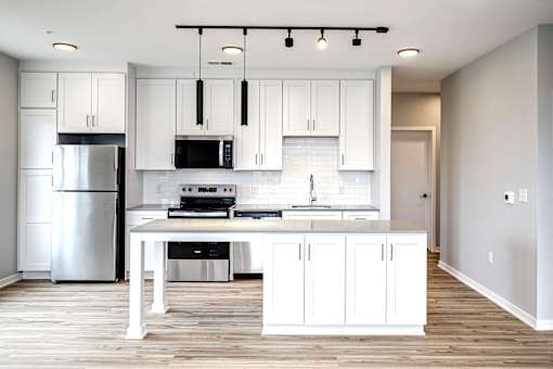 A modern kitchen with white cabinets and a wooden floor.