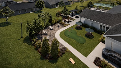 A golf course is surrounded by a green lawn and a few buildings.