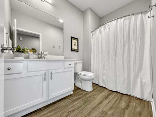 A white bathroom with a toilet, sink, and shower.