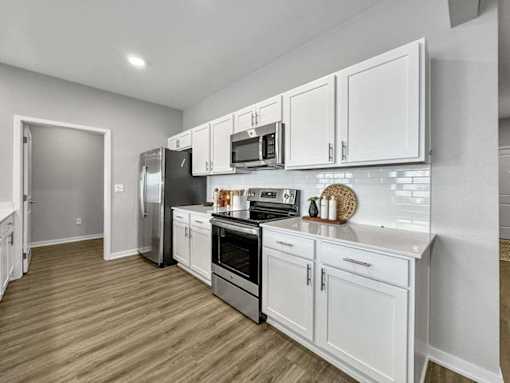 A kitchen with white cabinets and a black fridge.