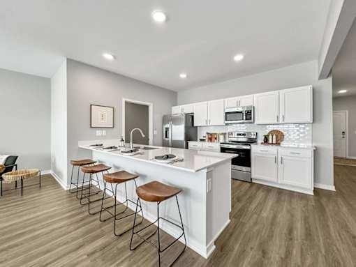 A modern kitchen with white cabinets and a long island.