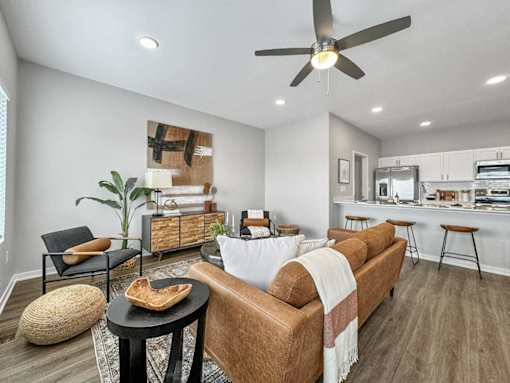 A living room with a brown couch, a black table, and a ceiling fan.