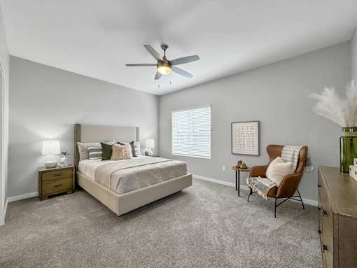A bedroom with a bed, chair, and a ceiling fan.