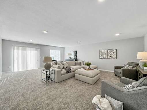 A living room with a grey sofa, a white couch, and a glass end table with a plant on it.