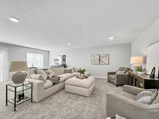 A living room with a large sectional sofa and a grey armchair.