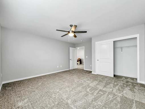 A room with a ceiling fan and carpeted floor.