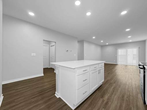A kitchen with white cabinets and wooden floors.