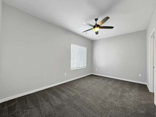 A room with a ceiling fan and carpeted floor.