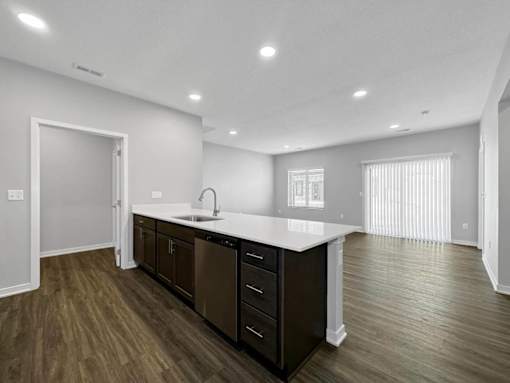 A modern kitchen with dark brown cabinets and a white countertop.