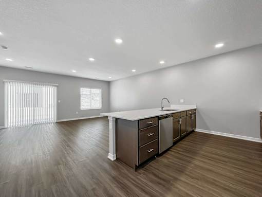 A kitchen with a white countertop and wooden flooring.