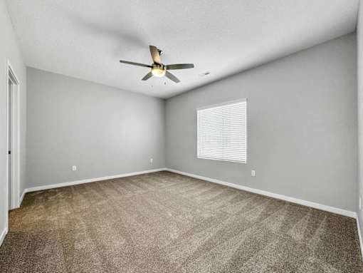 A room with a ceiling fan and a window with blinds.