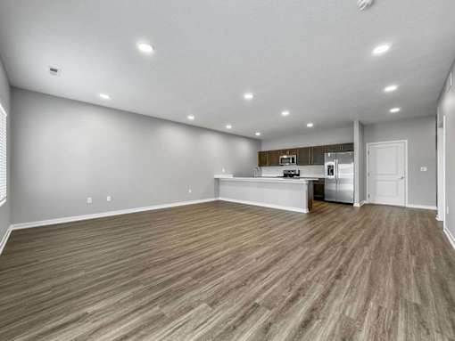 A spacious room with wooden flooring and a kitchenette in the corner.