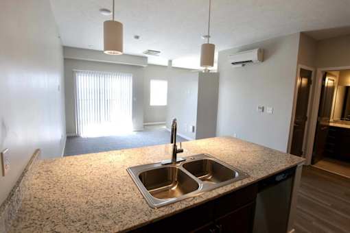 A kitchen with a granite countertop and a double sink.