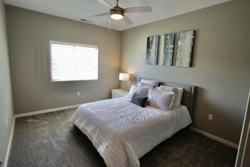 A bedroom with a bed, a ceiling fan, and a window.