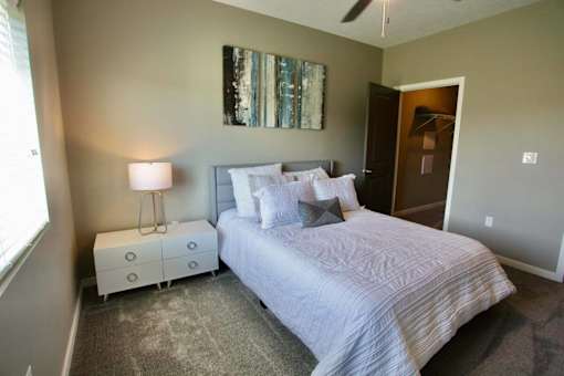 A bedroom with a bed, nightstand, and a painting on the wall.
