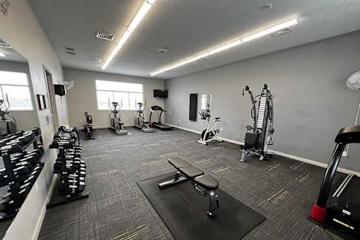 A gym with a variety of equipment including weights and cardio machines.