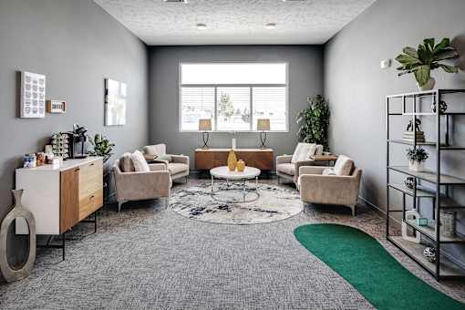 A living room with a grey carpet and a green rug.