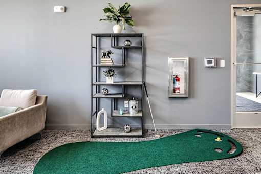 A grey shelf with various decorative items stands in a room with a green rug on the floor.