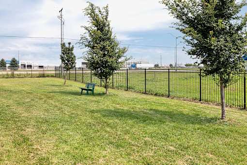 A park with a green bench and a black fence.