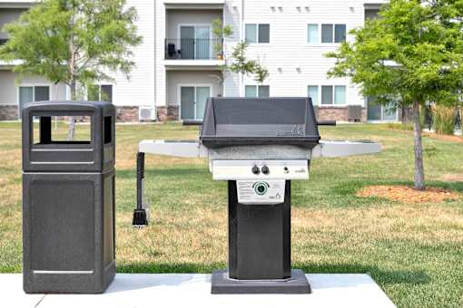 A black grill is in front of a white apartment building.