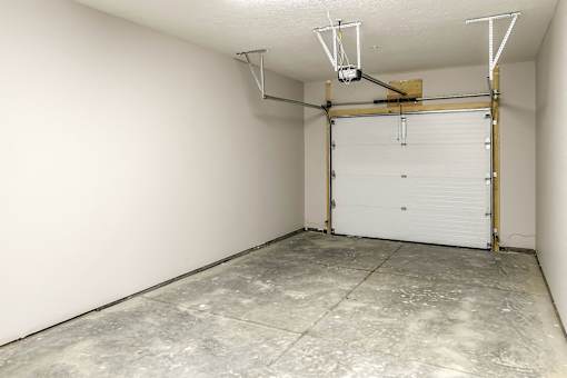A garage with a white door and a concrete floor.