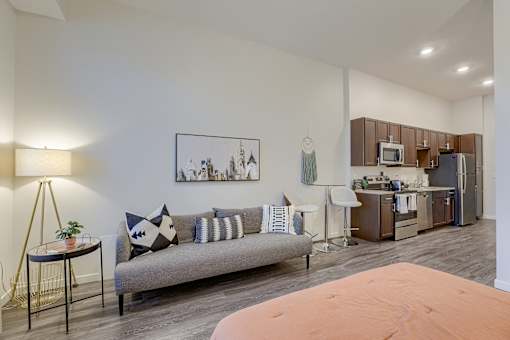 A living room with a grey sofa and a painting on the wall.