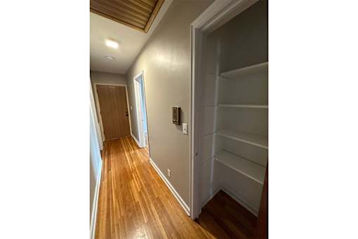 A hallway with a wooden floor and white walls.