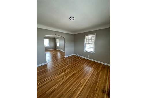 A room with wooden floors and two windows.