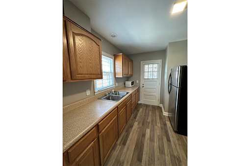 A kitchen with wooden cabinets and a black refrigerator.