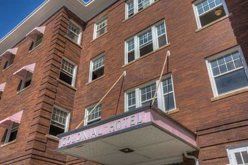 A brick building with a sign that says Colonial Hotel.