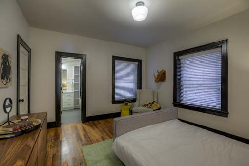 A bedroom with a bed, dresser, mirror, and window.