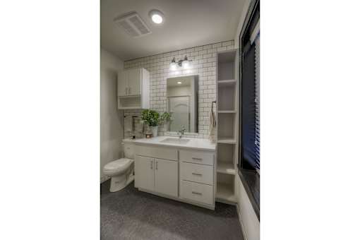 A bathroom with a toilet, sink, and mirror.