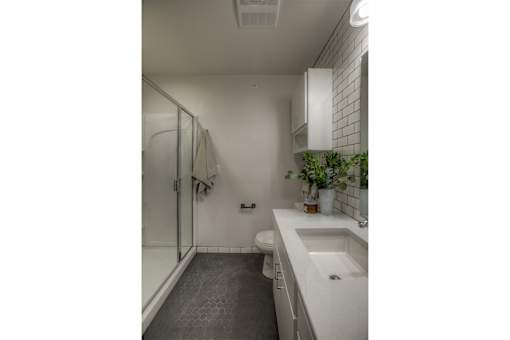 A white bathroom with a toilet, sink, and shower.