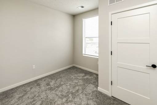 A room with a carpeted floor and a white door.