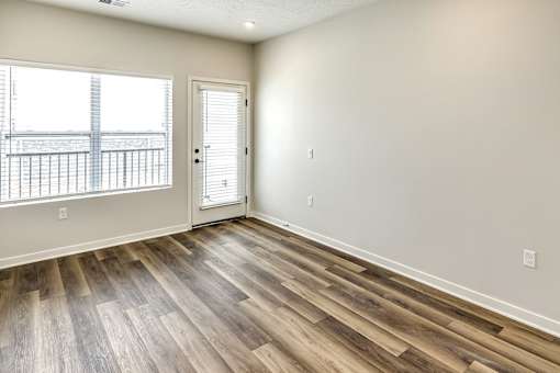 A room with a wooden floor and a door leading to a balcony.