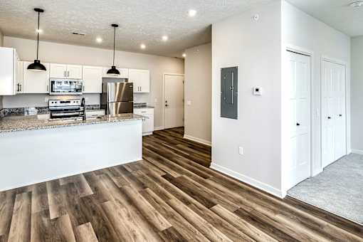 A kitchen with white cabinets and a wooden floor.