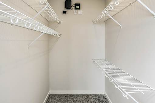 Empty white walk in closet with shelves.